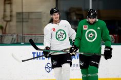 two men in green jerseys holding hockey sticks