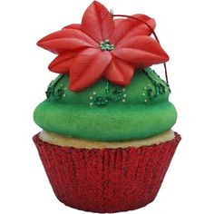 a cupcake with green frosting and red flowers on it's top, sitting in front of a white background