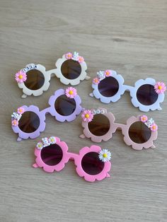 six pairs of sunglasses with flowers on them sitting on top of a wooden table next to each other