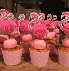 cupcakes with pink frosting and flamingos on top are sitting on a table