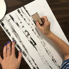 a woman is using a stamper to paint the birch trees on a piece of paper