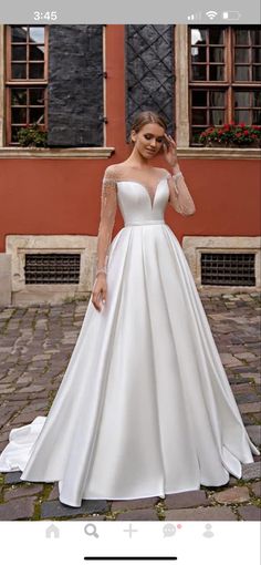 a woman wearing a white wedding dress standing in front of a red building with windows