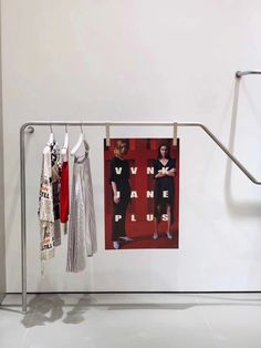 a rack with clothes hanging on it in front of a white wall and red background