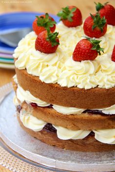 a cake with white frosting and strawberries on top is sitting on a plate