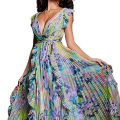 With This Winning Jovani 34412sc Creation, You Are Bound To Steal The Limelight. This Dress Is Sure To Turn Heads With Its Beautiful Floral Prints All Over And Pleated Detail On The Skirt. The Ruched Waistband Draws Attention To Your Curves. A Whimsical Touch Is Provided By The Short Flutter Sleeves, And The Deep V-Neckline Is Mirrored By The V-Open Back. The A-Line Skirt That Glides To The Sweeping Train Finishes The Ensemble, Creating A Sassy, Distinctive Look. This Jovani 34412sc Dress Exudes Purple Spring Gala Maxi Dress, Purple Spring Maxi Dress For Gala, Purple Maxi Dress For Spring Gala, Summer Wedding Guest Purple Maxi Dress, Purple V-neck Dress For Wedding Guest, Purple Summer Maxi Dress For Gala, Fitted Purple Pleated Maxi Dress, Lavender Dresses For Summer Gala, Purple Summer Dress For Wedding Guest