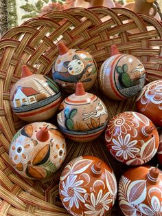 a wicker basket filled with lots of painted ceramic eggs on top of a table