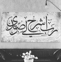 a black and white photo of a living room with arabic writing on the wall above a couch