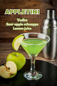 a green drink in a martini glass next to some apples