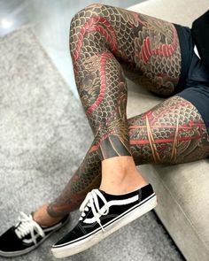 a man with tattoos on his legs and leggings is sitting on a couch