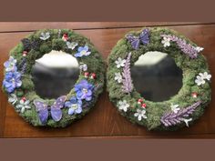 two wreaths with flowers and butterflies on them, one is made out of moss