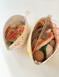 two baskets filled with yarn and knitting needles on top of a white table next to each other