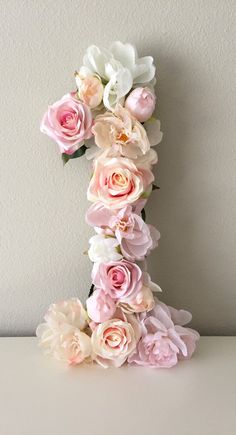 the letter is made out of flowers and has pink, white, and peach colors