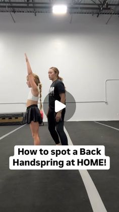 two women are standing on a tennis court and one is pointing at the ball with her hand