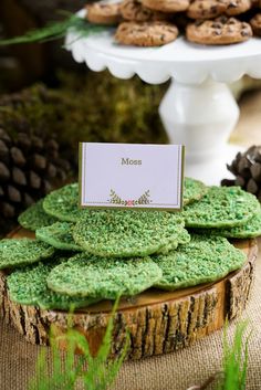 cookies are stacked on top of each other in front of a cake plate and pine cones