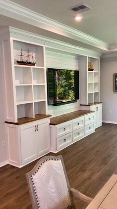 a large entertainment center with white cabinets and wood flooring in a living room area