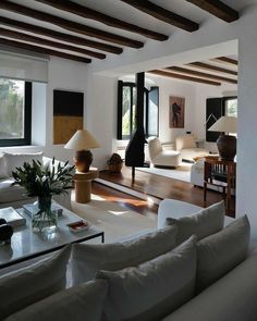 a living room filled with white furniture and lots of wooden beams on the ceiling,