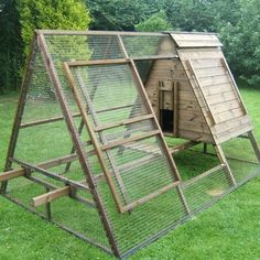 a large chicken coop in the middle of some grass