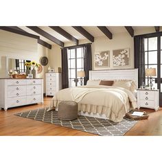 a white bed sitting on top of a wooden floor next to a dresser and mirror