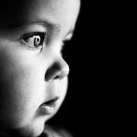 a black and white photo of a young child's face with one eye open