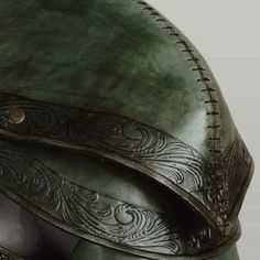 a close up view of a green helmet with intricate designs on the front and sides