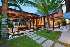 an outdoor living room and dining area with palm trees