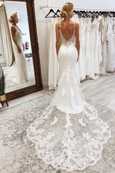 a woman standing in front of a mirror wearing a wedding dress