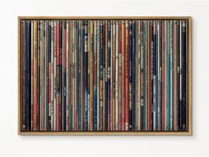 a wooden frame filled with lots of different types of music cassettes on the wall