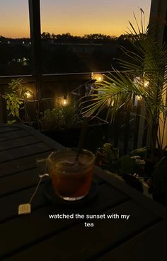 a cup of tea sitting on top of a table next to a window at night