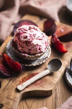 a wooden cutting board topped with ice cream and sliced plums