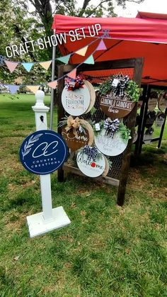 a sign that is in the grass near a red and white tent with some decorations on it