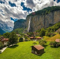 a village in the mountains with a waterfall coming out of it's cliff face