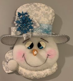 a stuffed snowman wearing a white hat and scarf with blue flowers on it's head