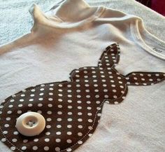 a white shirt with brown and white polka dot print on the front, and a button in the back