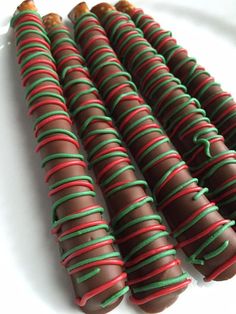 chocolate covered candy sticks with red, green and gold stripes on them sitting on a white surface