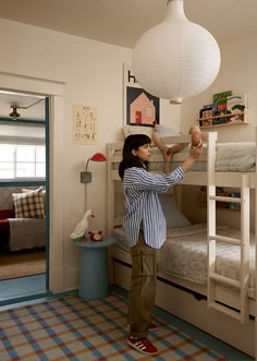 a woman standing on top of a bunk bed next to a child's bed