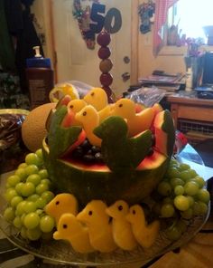 a watermelon carved to look like birds and grapes