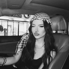 a woman sitting in the back seat of a car wearing a bandana on her head