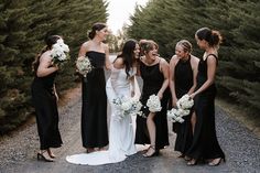 a group of women standing next to each other in front of some bushes and trees