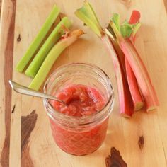 some celery sticks are next to a jar of food on a wooden table