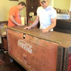 two men are standing next to an old chest that has been turned into a bed