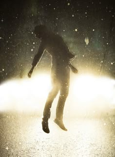 a person jumping in the air on a street at night with bright light coming from behind