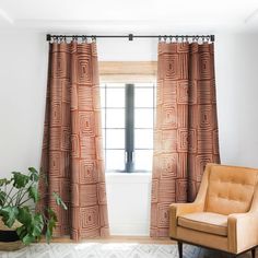 an orange chair sitting in front of a window next to a potted green plant