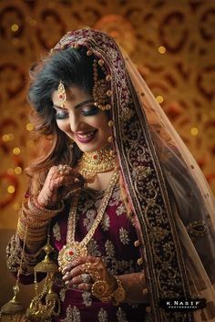 a woman in a bridal outfit with jewelry on her hands and smiling at the camera