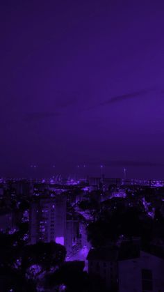 the city is lit up at night with purple lights in the sky and buildings below