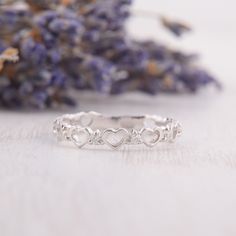 a silver ring with hearts on it sitting next to lavender flowers