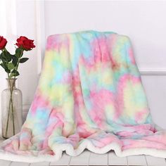 a pink, blue and yellow tie dye blanket sitting on top of a white tile floor