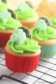 cupcakes with green frosting and shamrock decorations on top are sitting on a cooling rack