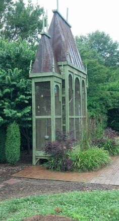 a green birdcage sitting in the middle of a garden