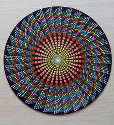 a colorful circular design is shown on a wooden surface with red and blue dots in the center