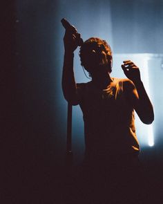 a woman standing in front of a microphone with her hand up to the side and headphones on